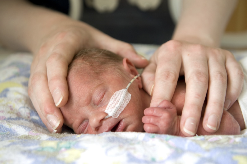 Photo of a tiny baby in NICU with hands touching them